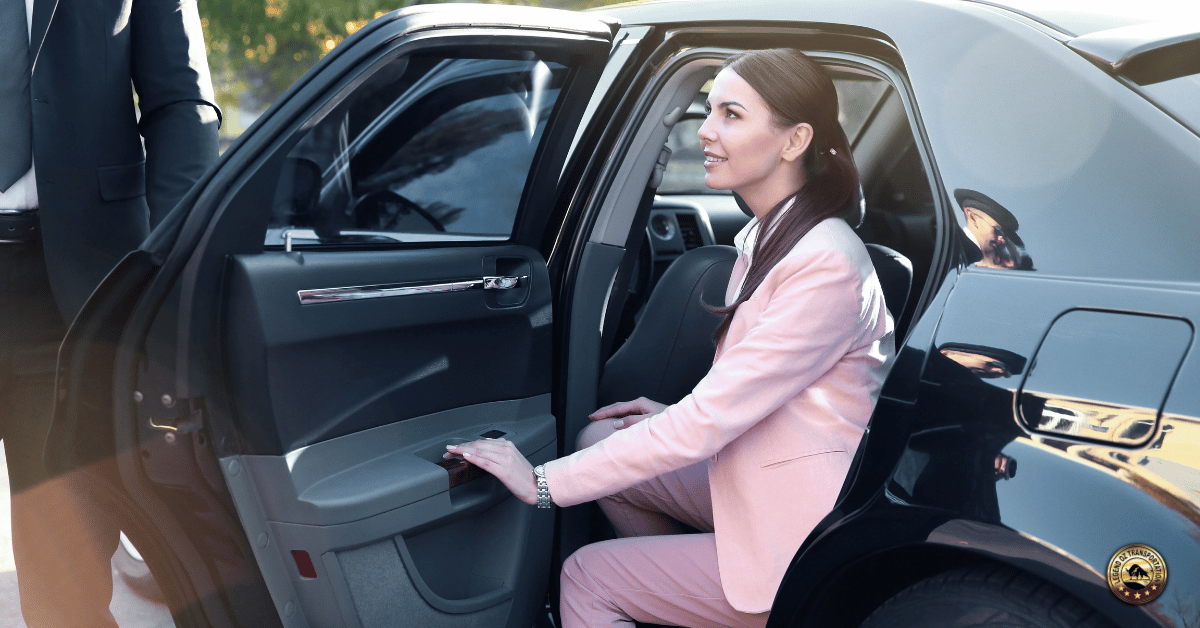 Businesswoman entering a luxury chauffeur vehicle with assistance from a professional driver